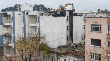 İş makinası yıkım için ağır hasarlı binanın üzerine çıkarıldı