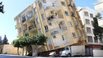 İskenderun'da yan yatan ağır hasarlı binayı altında kalan kamyonet ayakta tutuyor